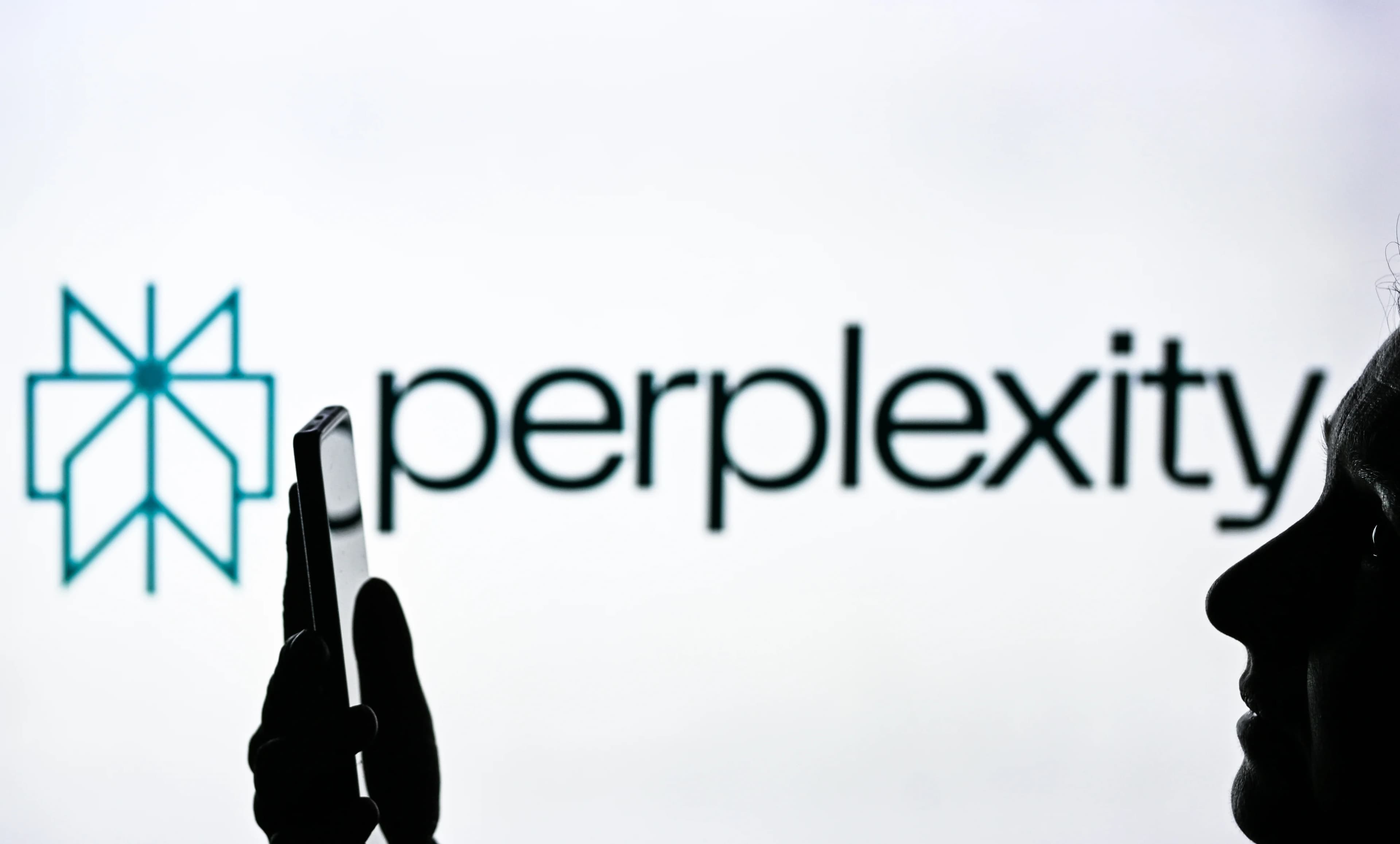 Perplexity logo on a white background with a person holding up a phone in silhouette